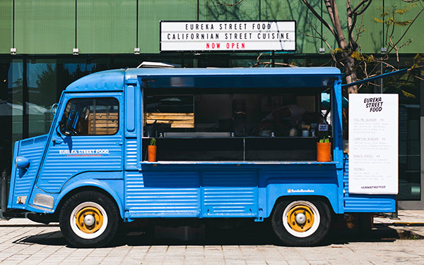 an image of a blue food truck in from of an office building.