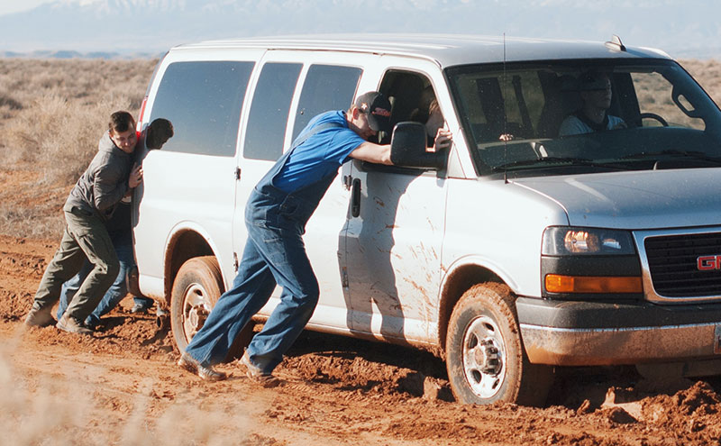 People trying to help a van stuck in a rut.